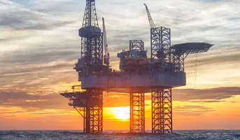 Offshoreoil platform in ocean with sunset in background